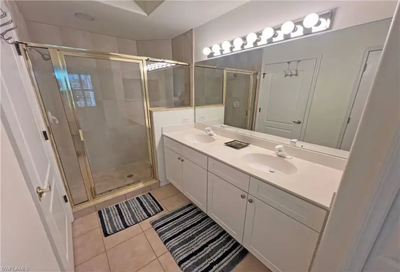 Master bathroom with a shower with door, tile flooring, and dual vanity