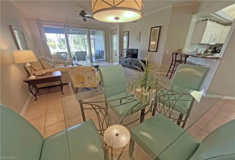 Tiled dining room with ceiling fan and crown molding