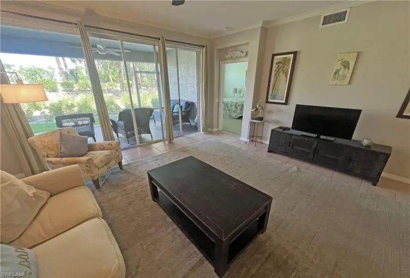 Living room featuring a healthy amount of sunlight, tile flooring, and ornamental molding