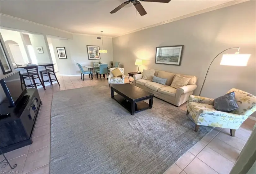 Living room with tile floors, ceiling fan, and ornamental molding