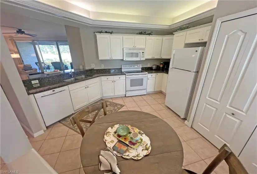 Kitchen with granite countertops, sink, white modern cabinets, crown lighting, and light tile floors