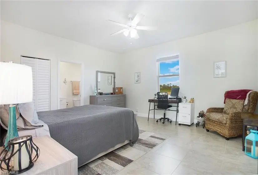 Bedroom with ceiling fan, connected bathroom, and light tile floors