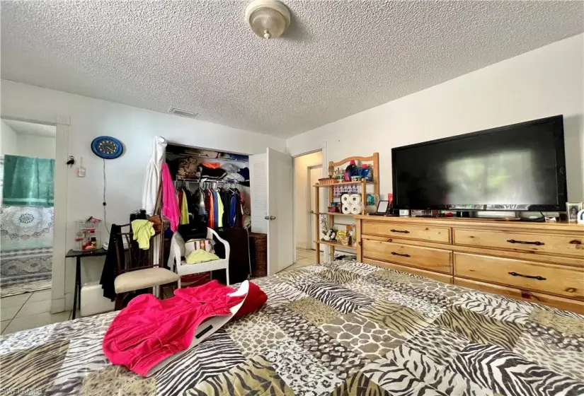 Bedroom with a closet, a textured ceiling, and light tile floors