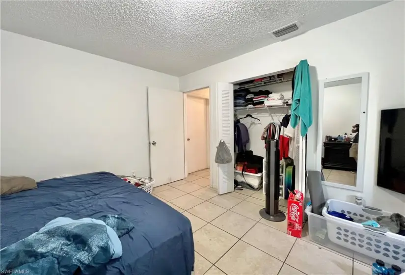 Tiled bedroom featuring a closet and a textured ceiling