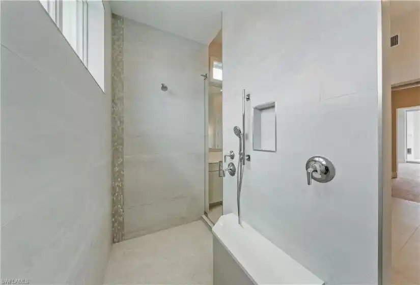 The primary bathroom features a soothing color scheme, custom tile designs, linen closet, water closet, and an impressive shower and dual vanity configuration.