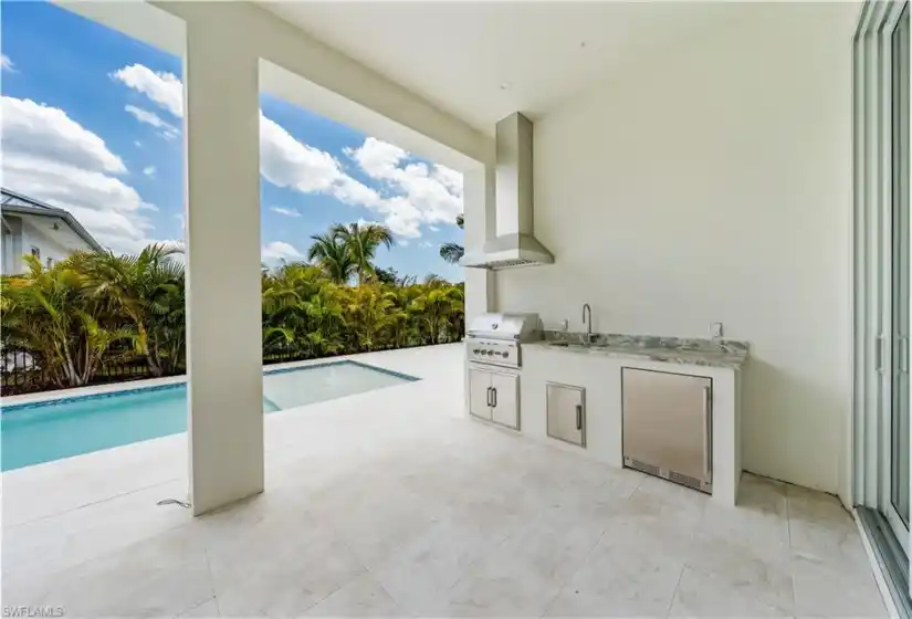 The outdoor kitchen includes a natural gas Coyote grill and SS under counter refrigerator with Krauss sink.